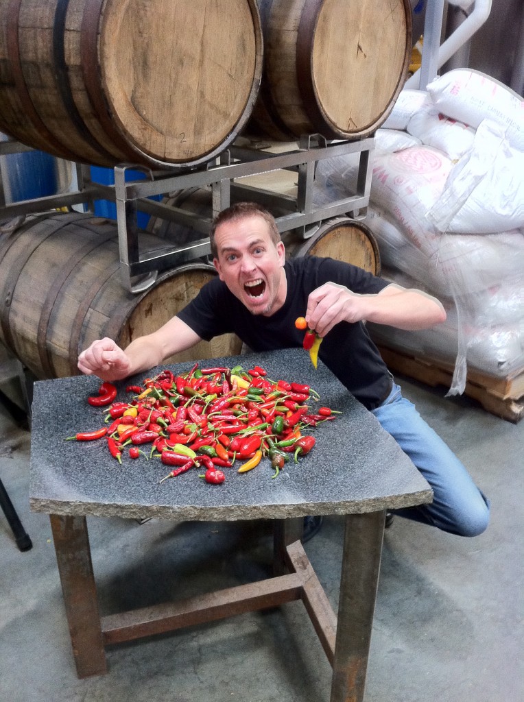 Greg holding chili peppers in front of a pile of chili peppers