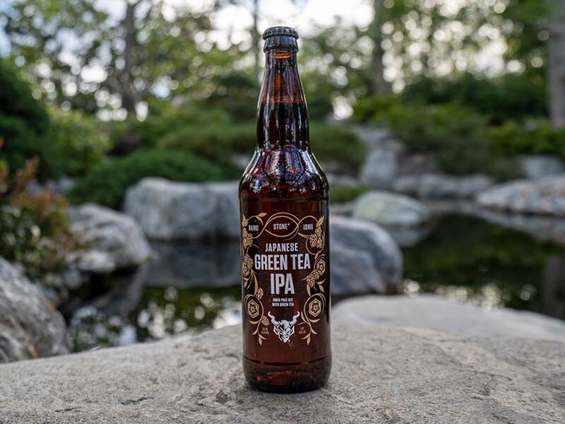 Baird / Ishii / Stone Japanese Green Tea IPA bottle in front of water and rocks