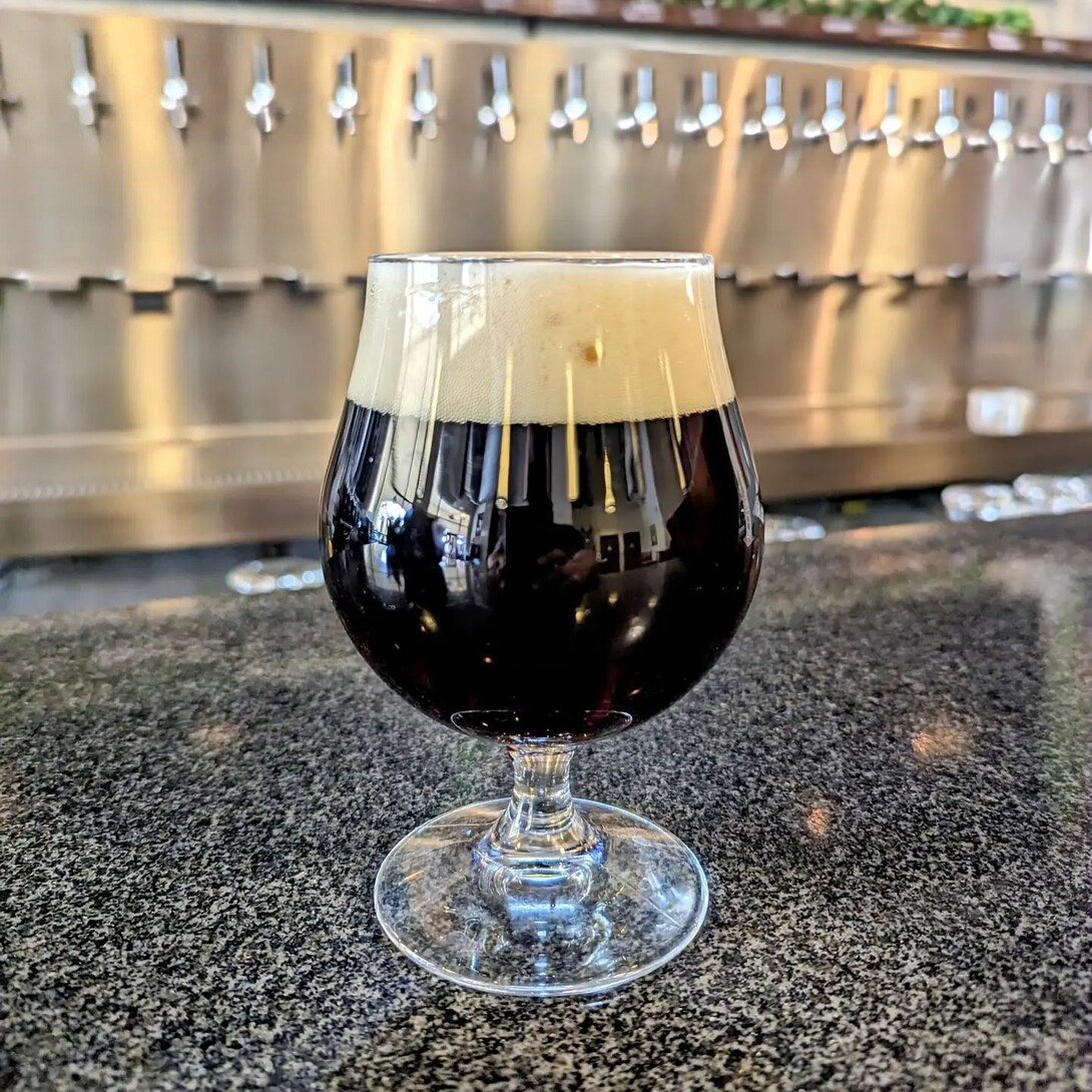 a glass of a dark beer on the bar of stone brewing pasadena
