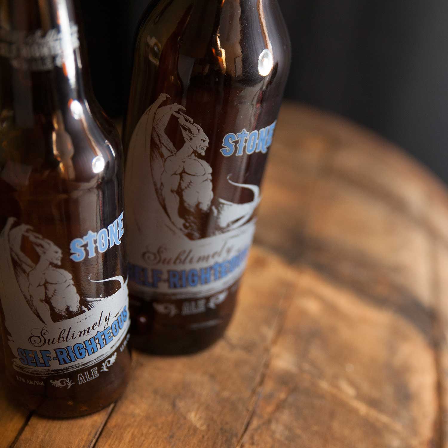 Bottles of Stone Sublimely Self-Righteous Ale on a barrel