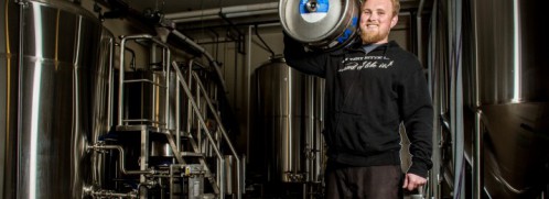 Kris Ketcham holding a barrel of beer in the brewery