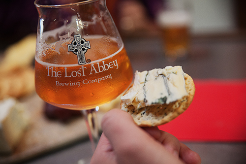 Glass of the lost abbey beer with a cracker and cheese