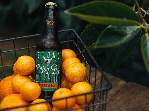 Stone Enjoy By 07.25.16 Tangerine IPA in a basket of tangerines