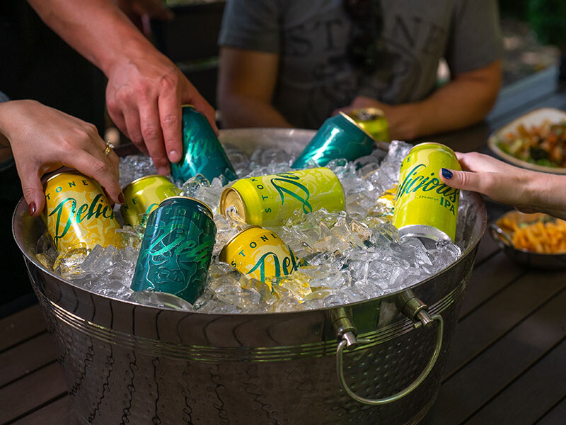hand pull out a stone delicious ipa, a stone delicious double ip and a stone delicious citrus ip from a bucket of ice