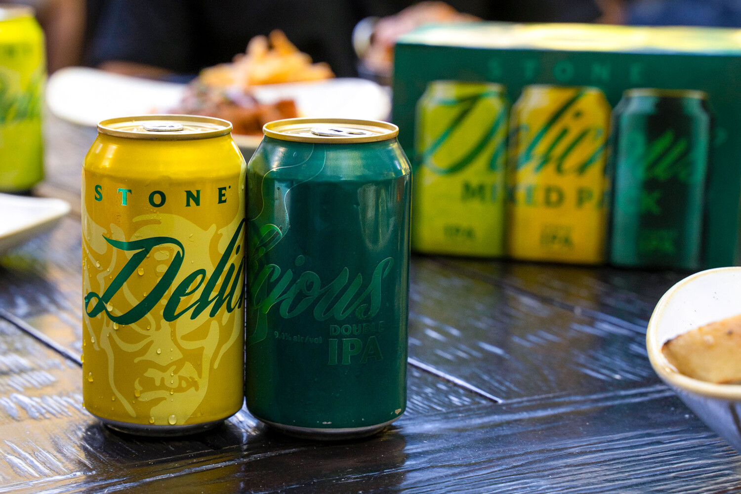 a can of stone delicious citrus ipa and stone delicious double ipa on a table with food