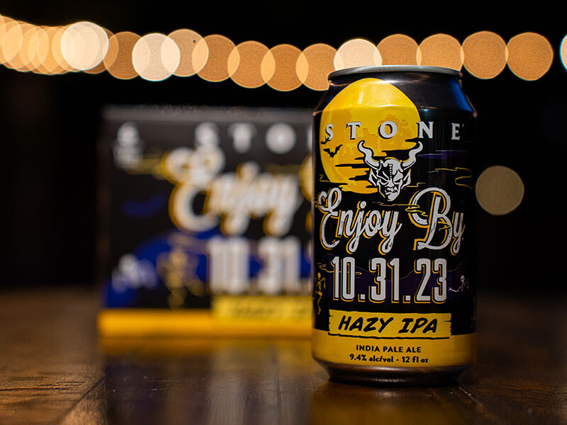 a can and a six-pack of Stone Enjoy By 10.31.23 Hazy IPA beer at night