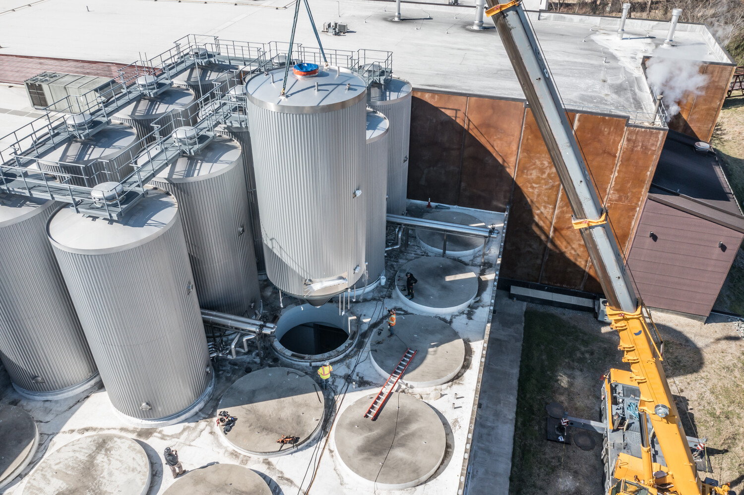 brewing tank being lifted by a crane