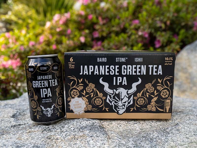 Baird / Ishii / Stone Japanese Green Tea IPA can and six-pack in front of flowers