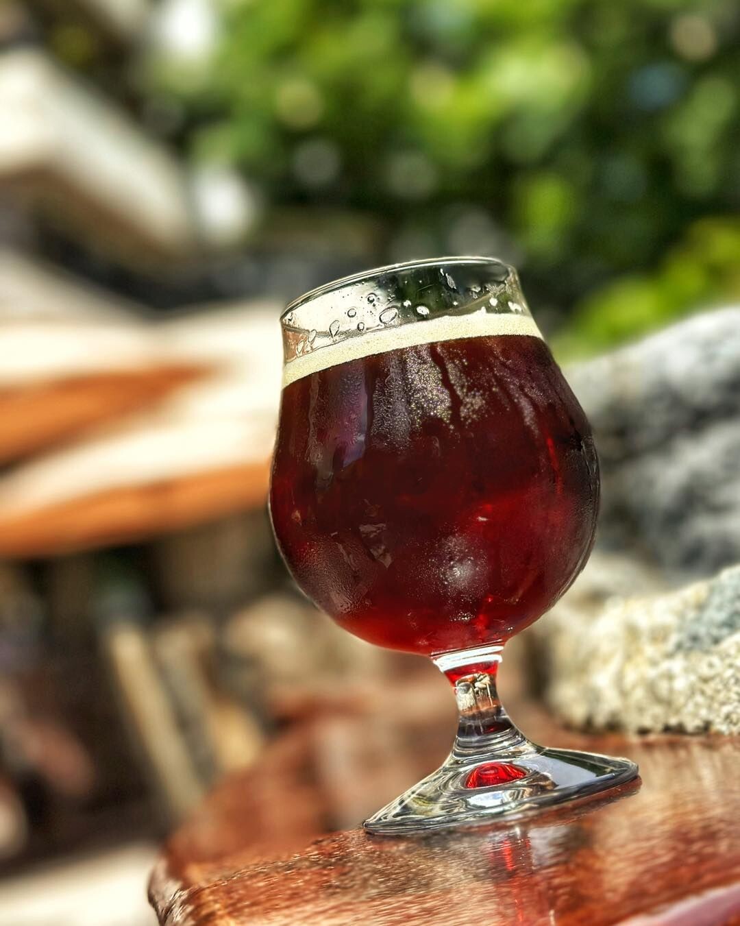 a glass of red ale on an outdoor bar counter at stone brewing tap room kettner in downtown little italy san diego