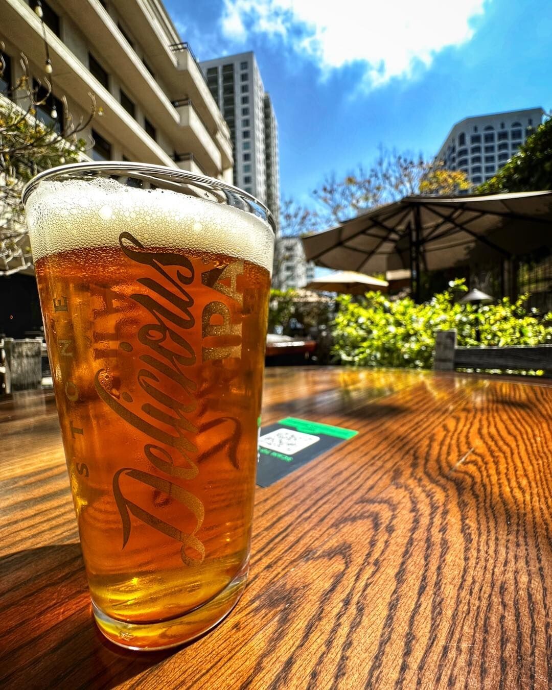 a glass of stone delicious ipa on a table at stone brewing tap room kettner in downtown little italy san diego