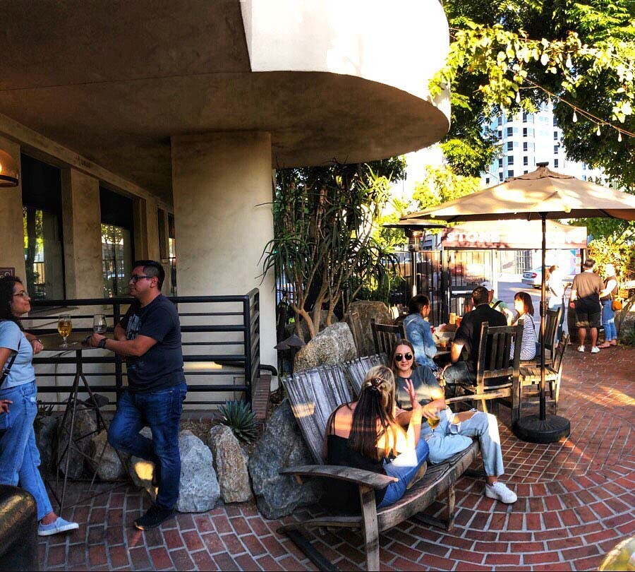 people outside enjoying the gardens of the stone brewing tap room kettner in downtown little italy san diego