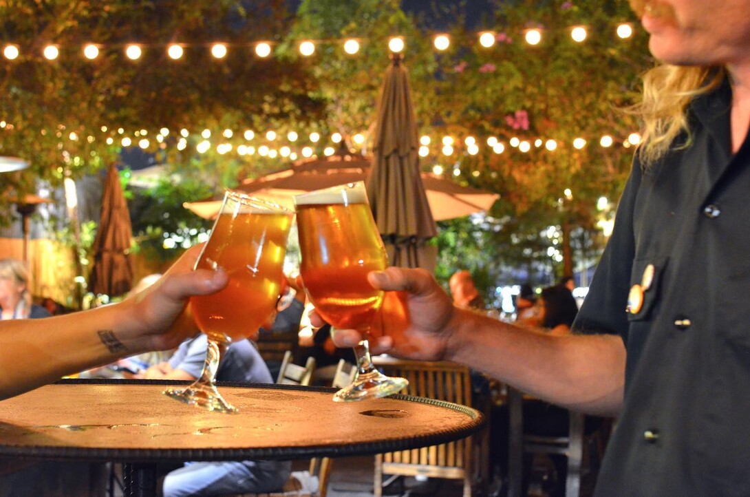 two people cheersing in the gardens of the stone brewing tap room oceanside