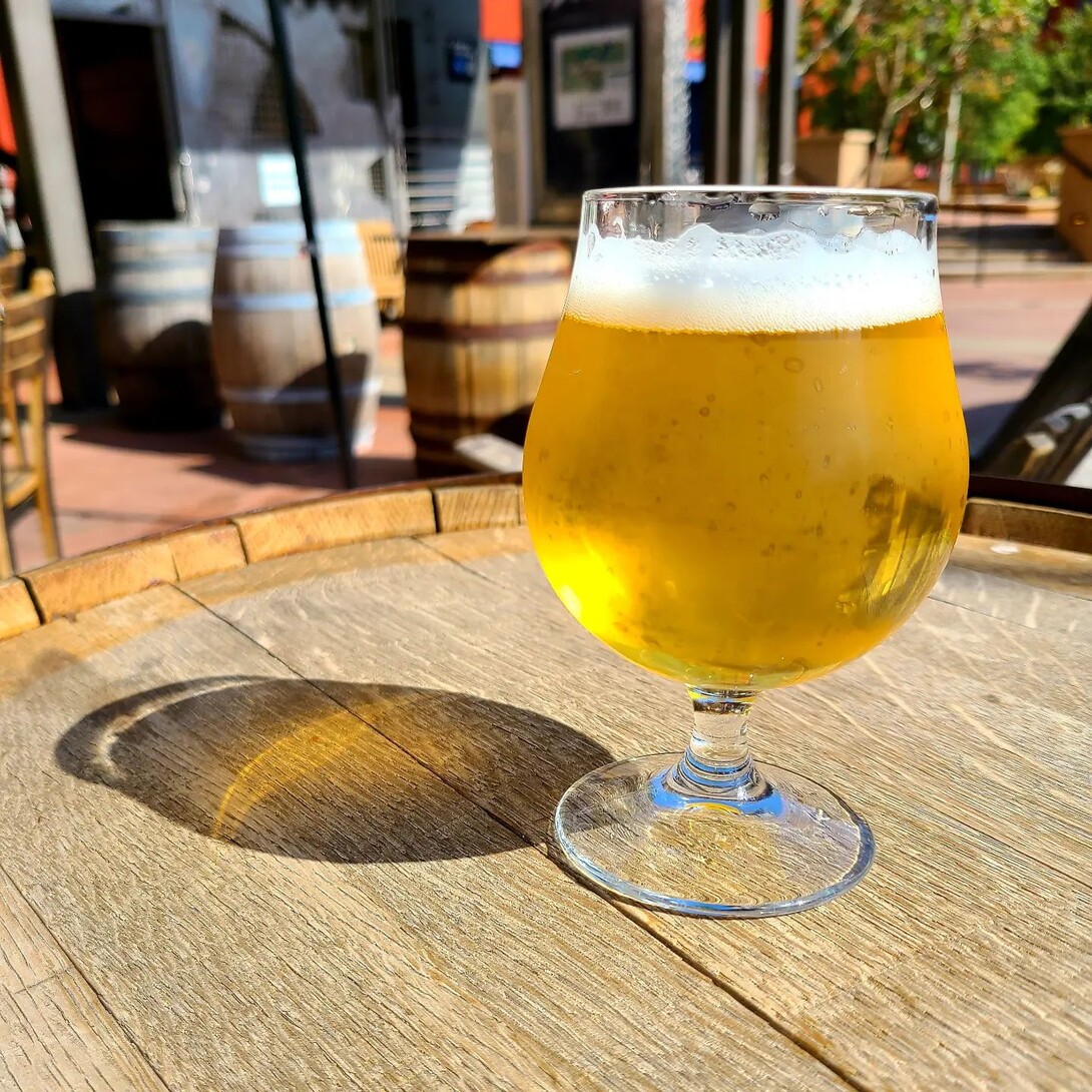 a glass of beer on a barrel at stone brewing pasadena